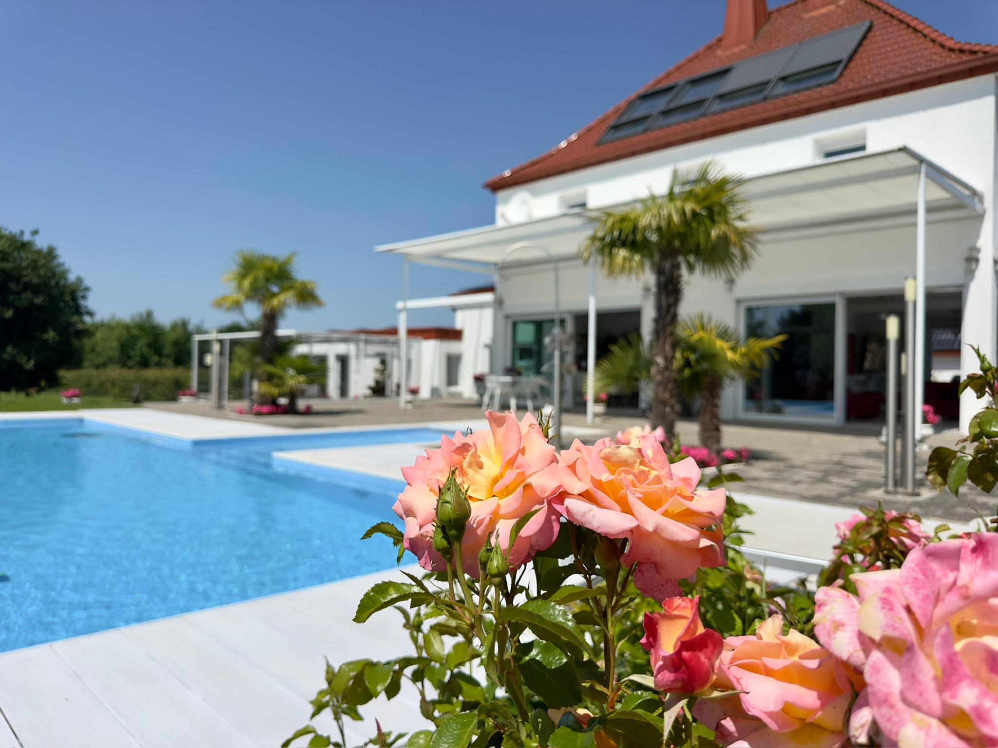 Eleganter Poolbereich mit Rosen und Blick auf das Anwesen als Kulisse für Empfang und Feier